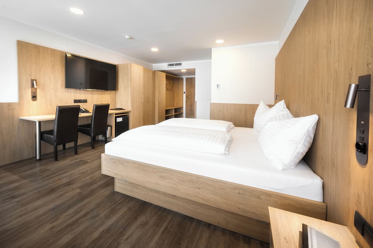Una habitación de hotel moderna con una cama grande, un escritorio y un televisor de pantalla plana.