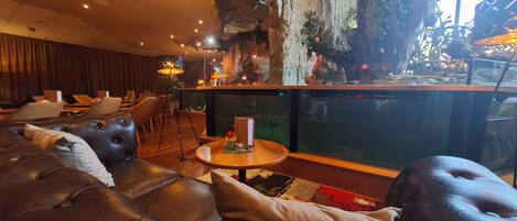 Un espace détente moderne avec des canapés en cuir, une table ronde en bois et un grand aquarium.