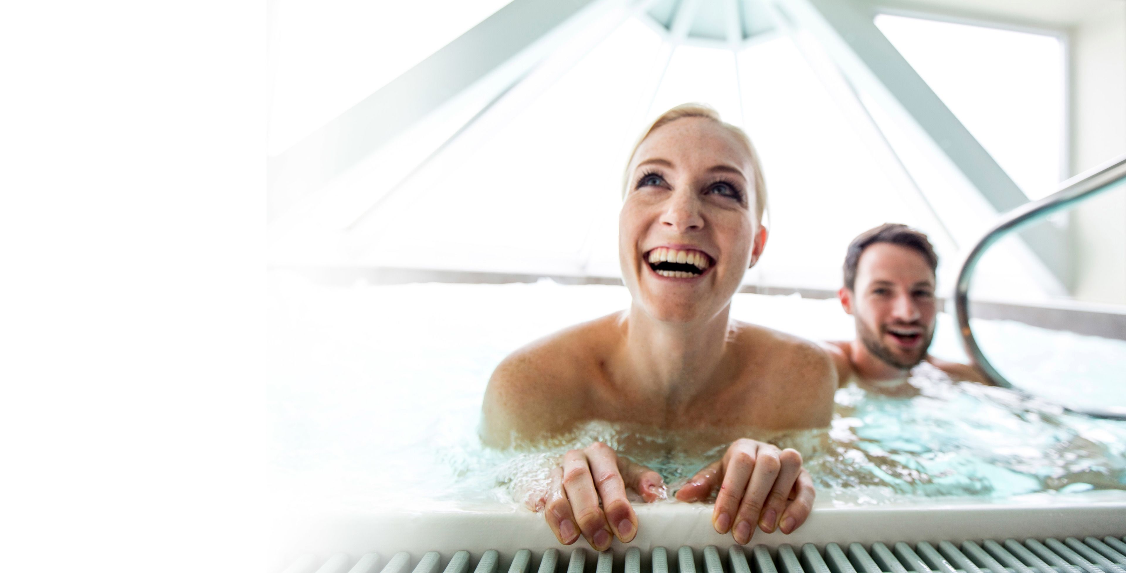 Una persona en un jacuzzi bajo una estructura de techo moderna y geométrica.