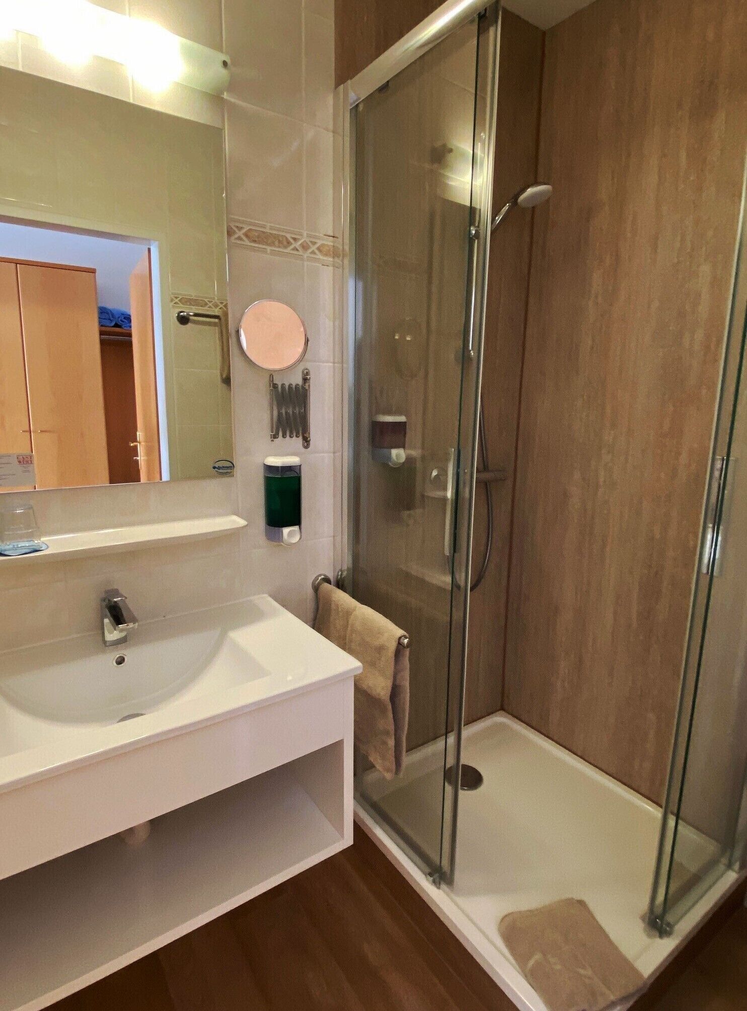 Een moderne badkamer met een douchecabine van glas, een wit wastafelmeubel en een spiegel.