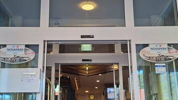 The entrance of a hotel with a chandelier, double doors, and a red carpet.