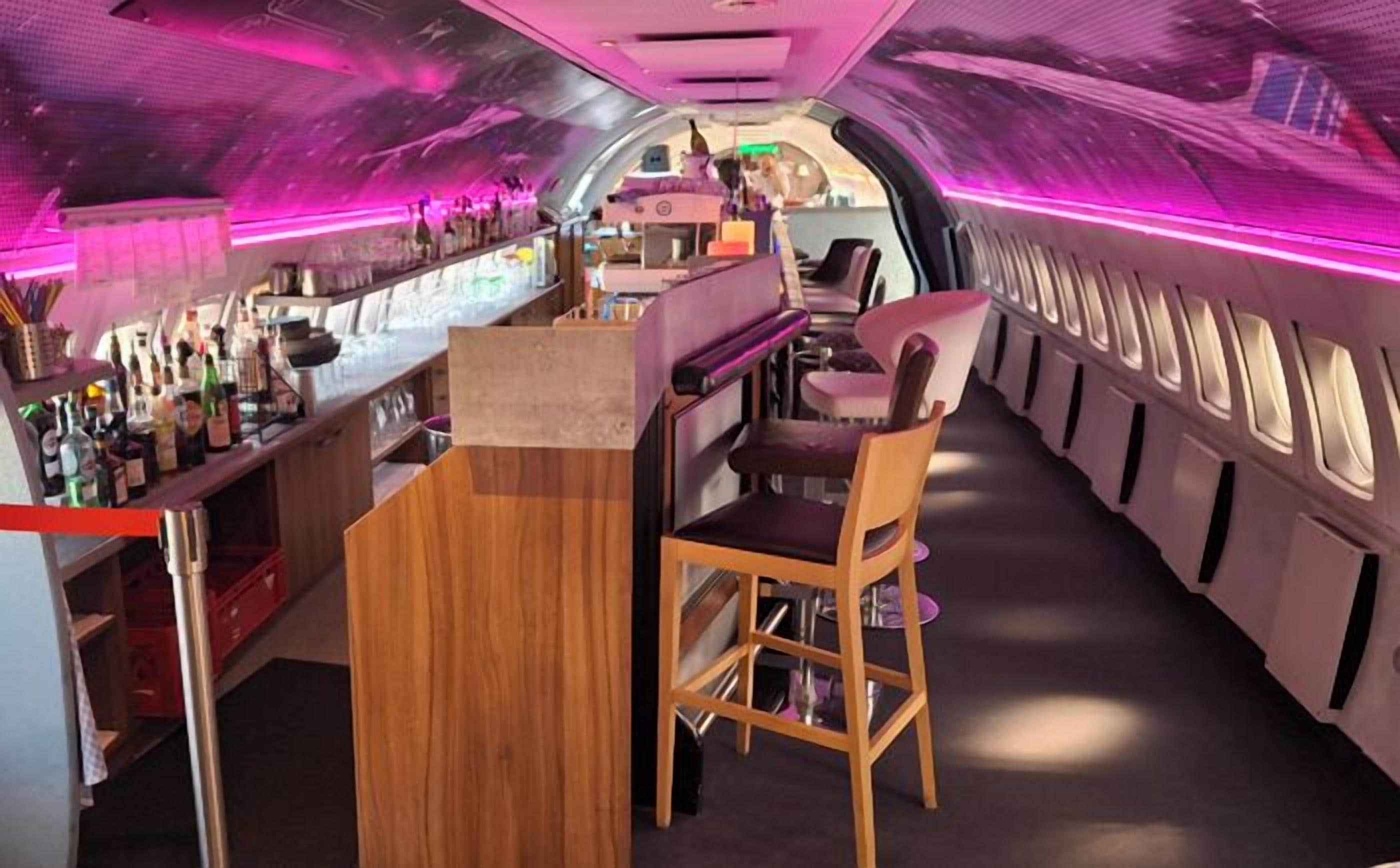 A bar area with a wooden counter, bar stools, and a seating area with a chair.