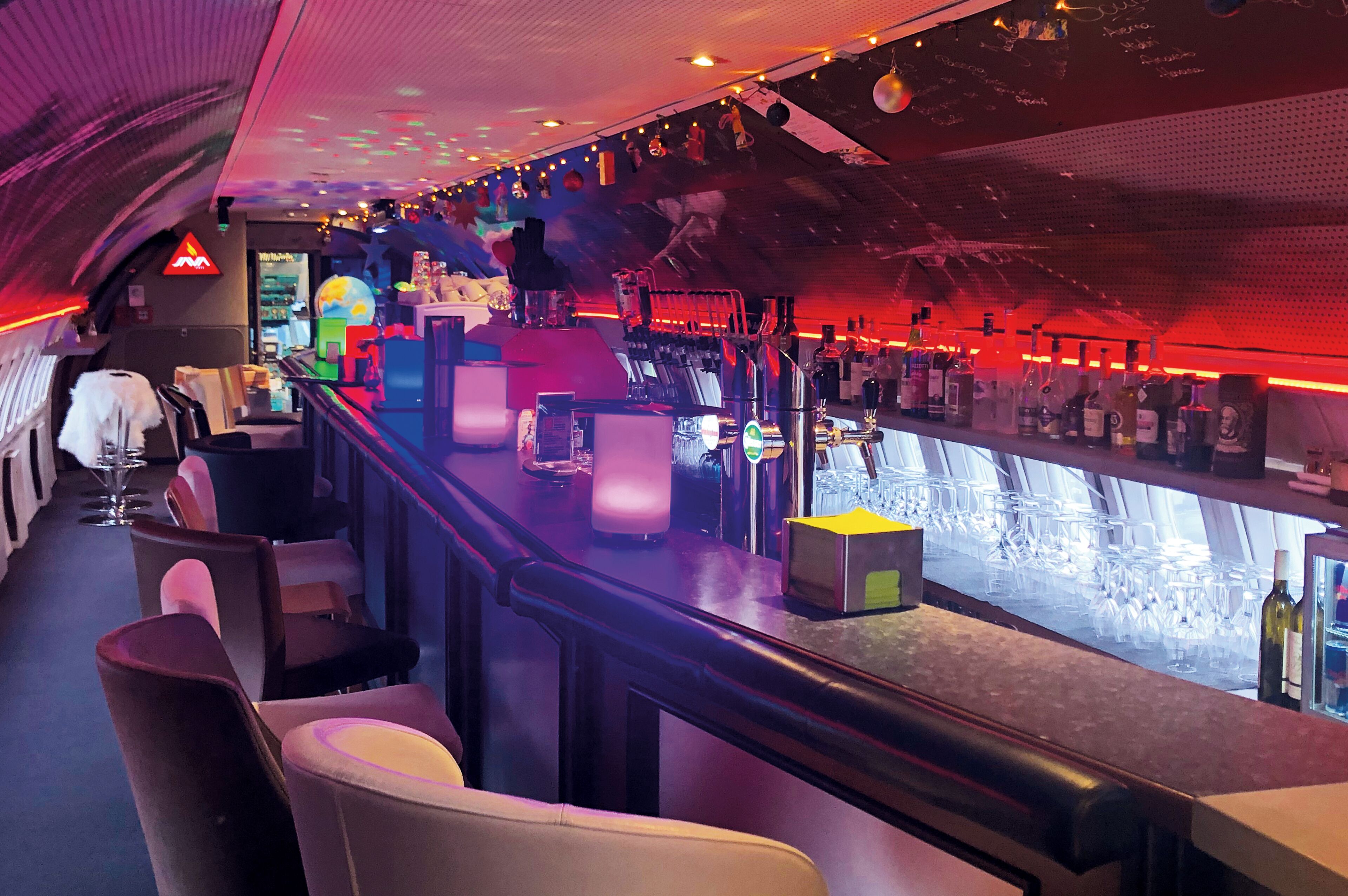 A bar area with seating, a bar counter, and a variety of bottles and glasses.