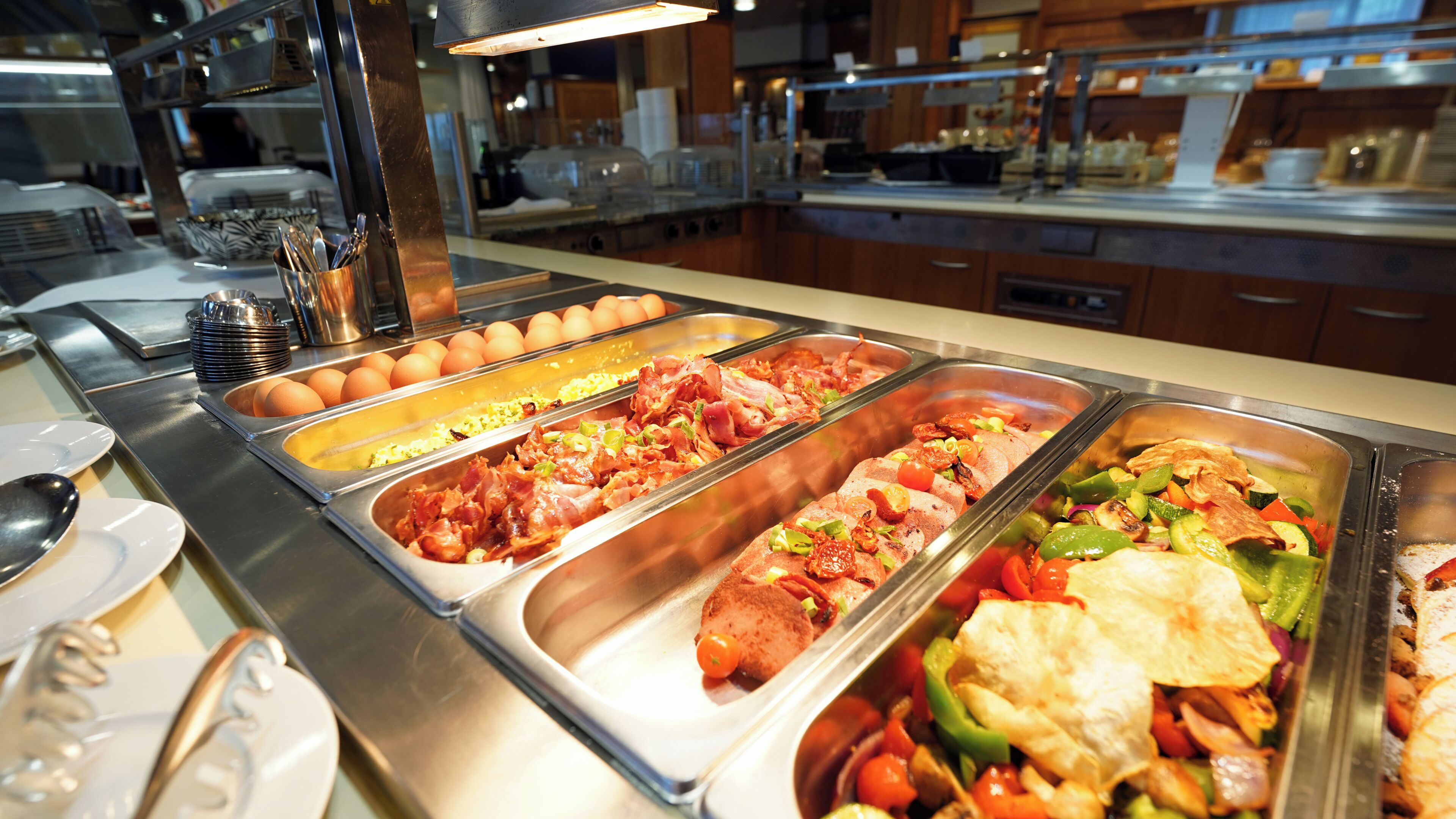A buffet with various food options including meats, vegetables, and eggs.