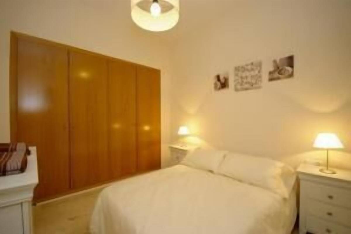 A bedroom with a bed, bedside tables, a wardrobe, and wall-mounted artwork.