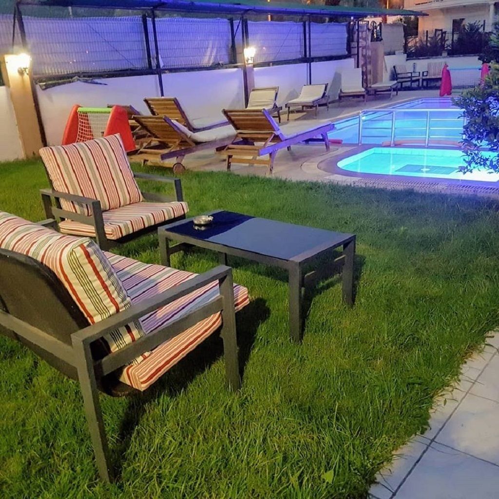 A backyard with a pool, lounge chairs, and a dining table.