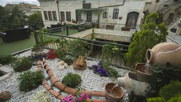 Un jardín en la azotea con macetas de terracota, una hamaca y diversas plantas.
