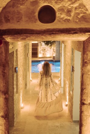 A corridor with stone walls and a pool visible in the distance. - Fresco Cave Suites & Mansions - Special Class (Ürgüp)