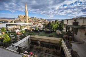 Un patio con plantas en macetas, mobiliario exterior y vistas a un pueblo histórico con una torre destacada.