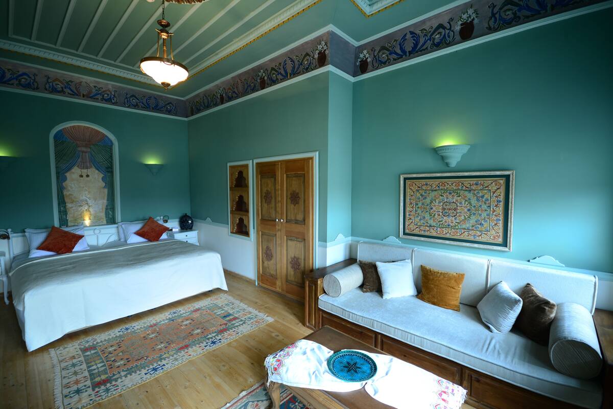 Un dormitorio con cama, sofá, mesa y una pared con diseños decorativos.