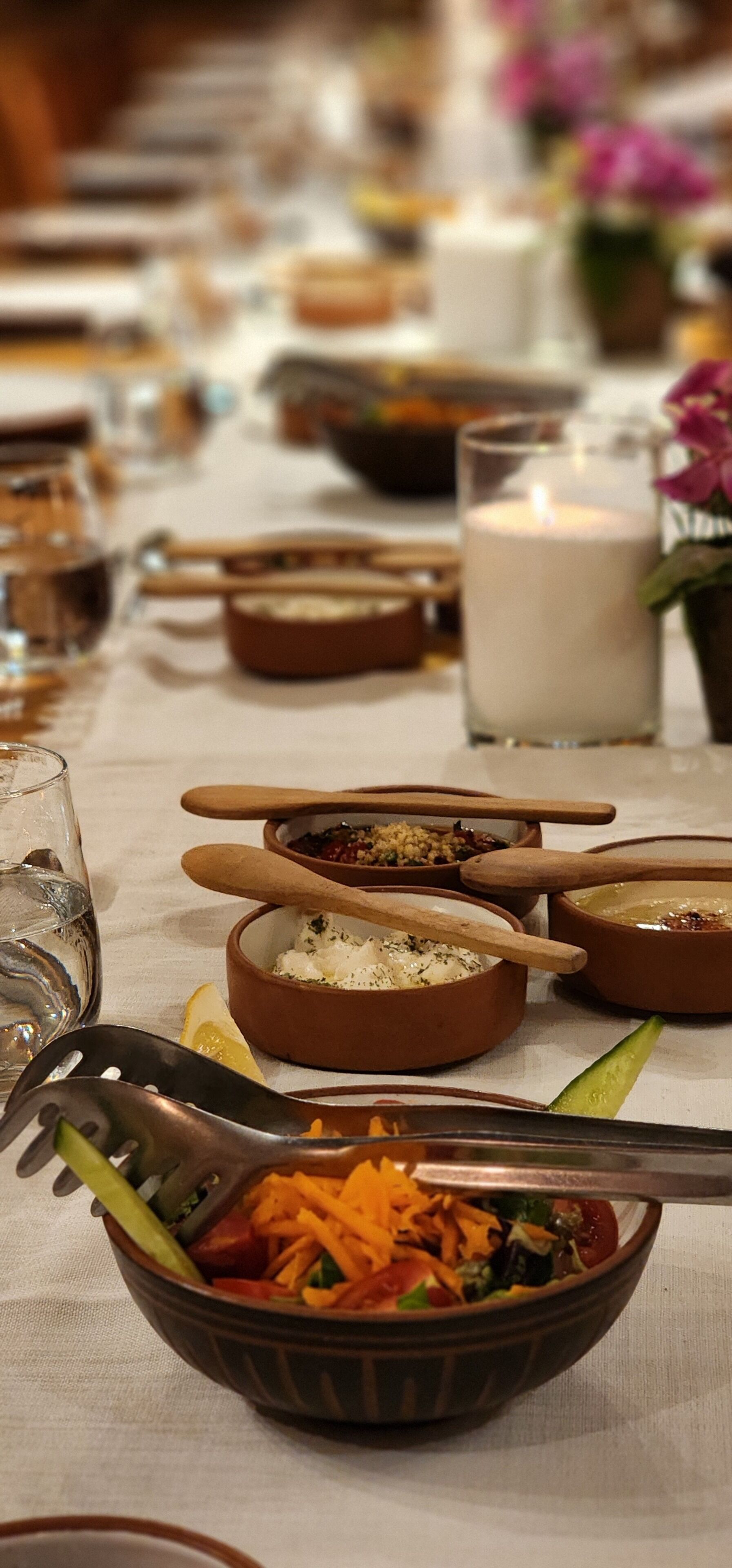 Una mesa servida con diversos platos, entre ellos una ensalada, tazones de comida y un vaso de leche.