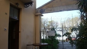 Un patio con una mesa y sillas, un letrero que indica habitaciones disponibles y una puerta con valla.