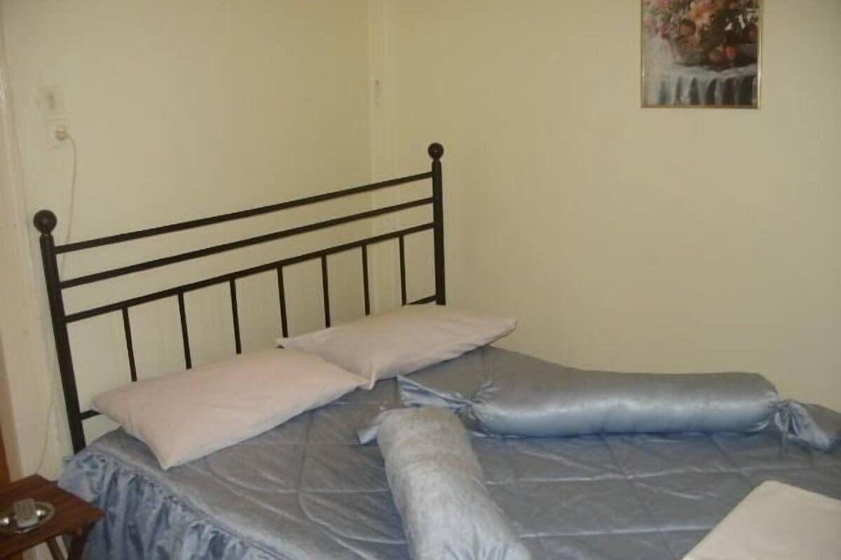A bed with a metal frame, a blue bedspread, and two pillows.
