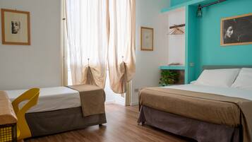 A hotel room with two beds, wooden flooring, and a teal accent wall.