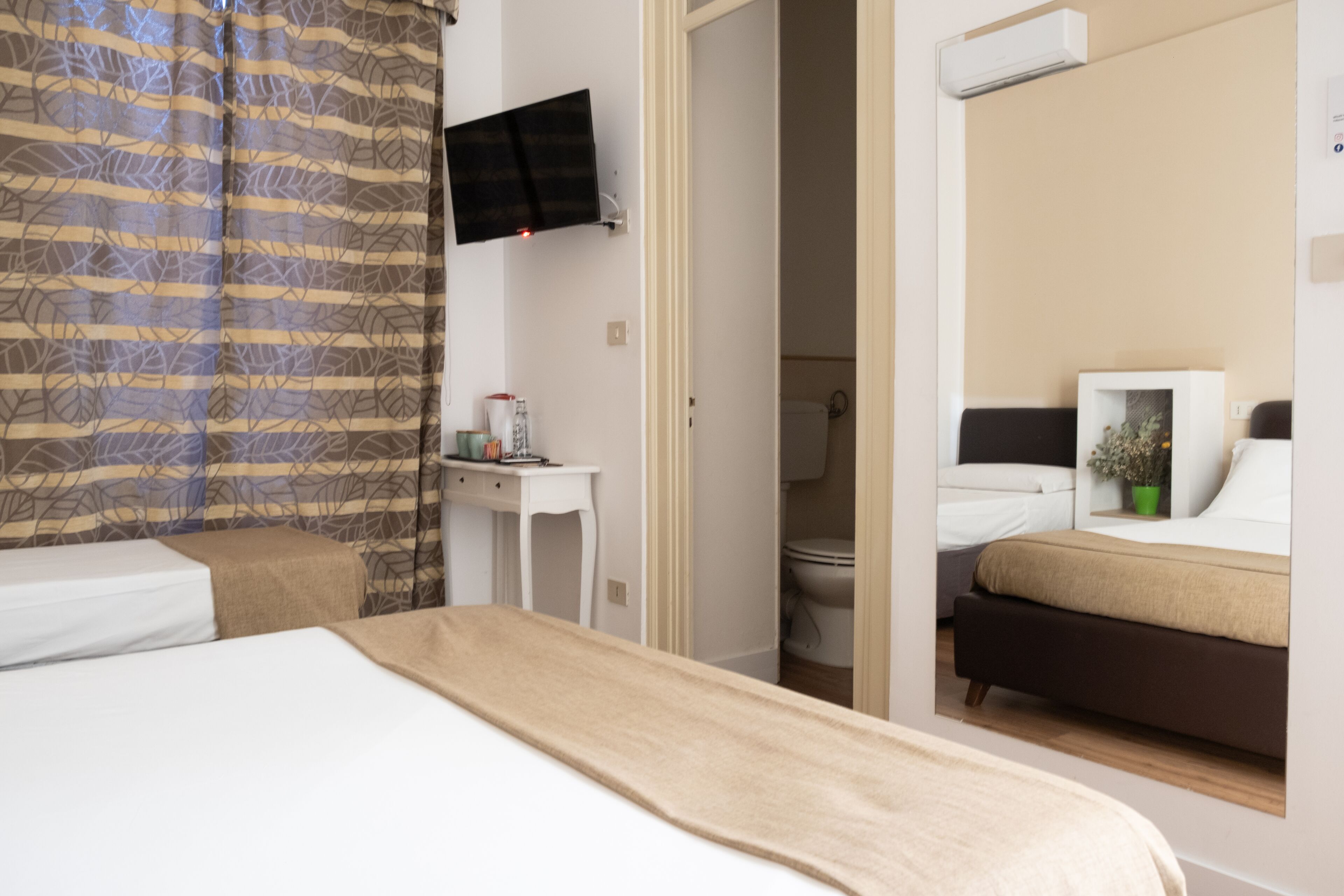 A hotel room with a bed, a desk, a television, and a bathroom visible through an open door.