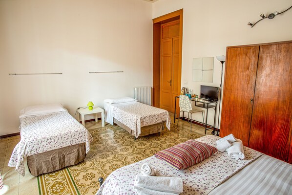 Una habitación de hotel con dos camas individuales, un escritorio con silla, un radiador y un armario.