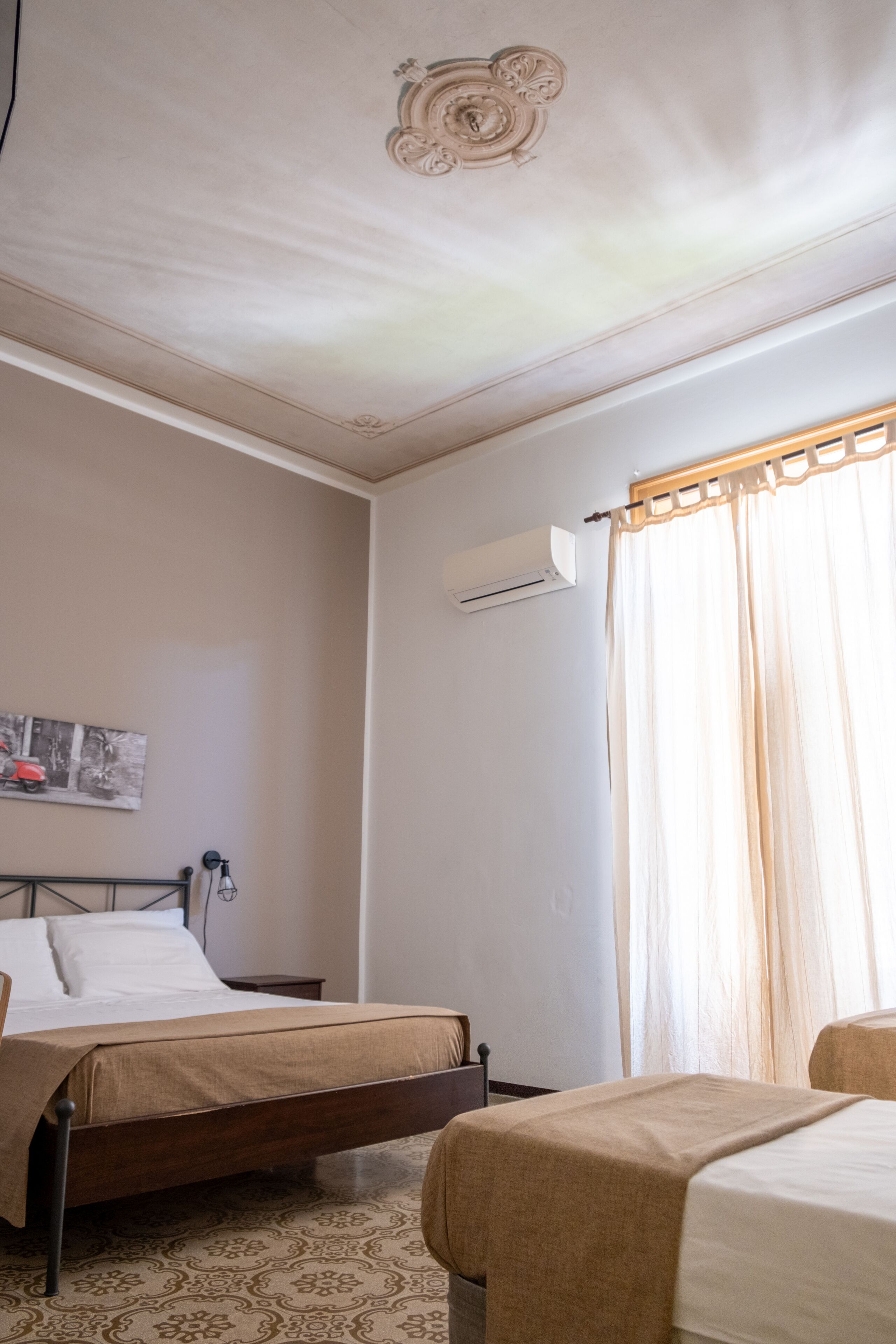 Una camera da letto con un letto, un comodino, un condizionatore e una finestra con tende.