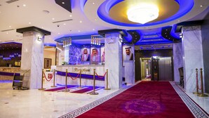 A hotel reception area with a red carpet, marble columns, and a chandelier. - Jazan Inn (Jizan)