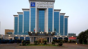 A modern building with a prominent sign reading "Jazan Inn" and multiple flags. - Jazan Inn (Jizan)