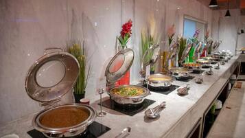 A buffet setup with various food stations, each with a covered serving dish and a spoon.