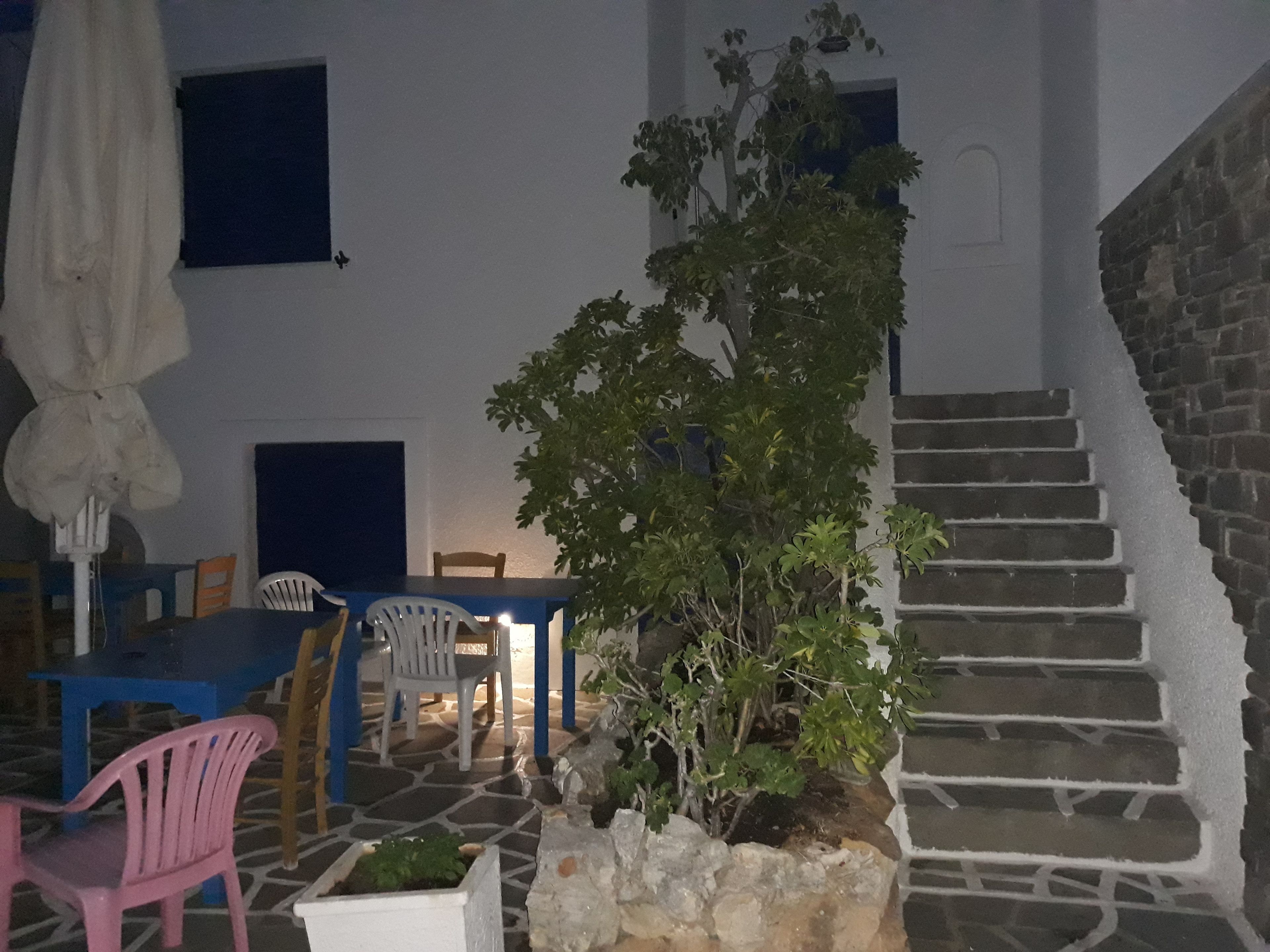 A courtyard with a table and chairs, a staircase, and a potted plant.