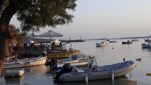 A marina with several boats docked, a restaurant with outdoor seating, and a calm water body. - Holidays in Paros (Paros)