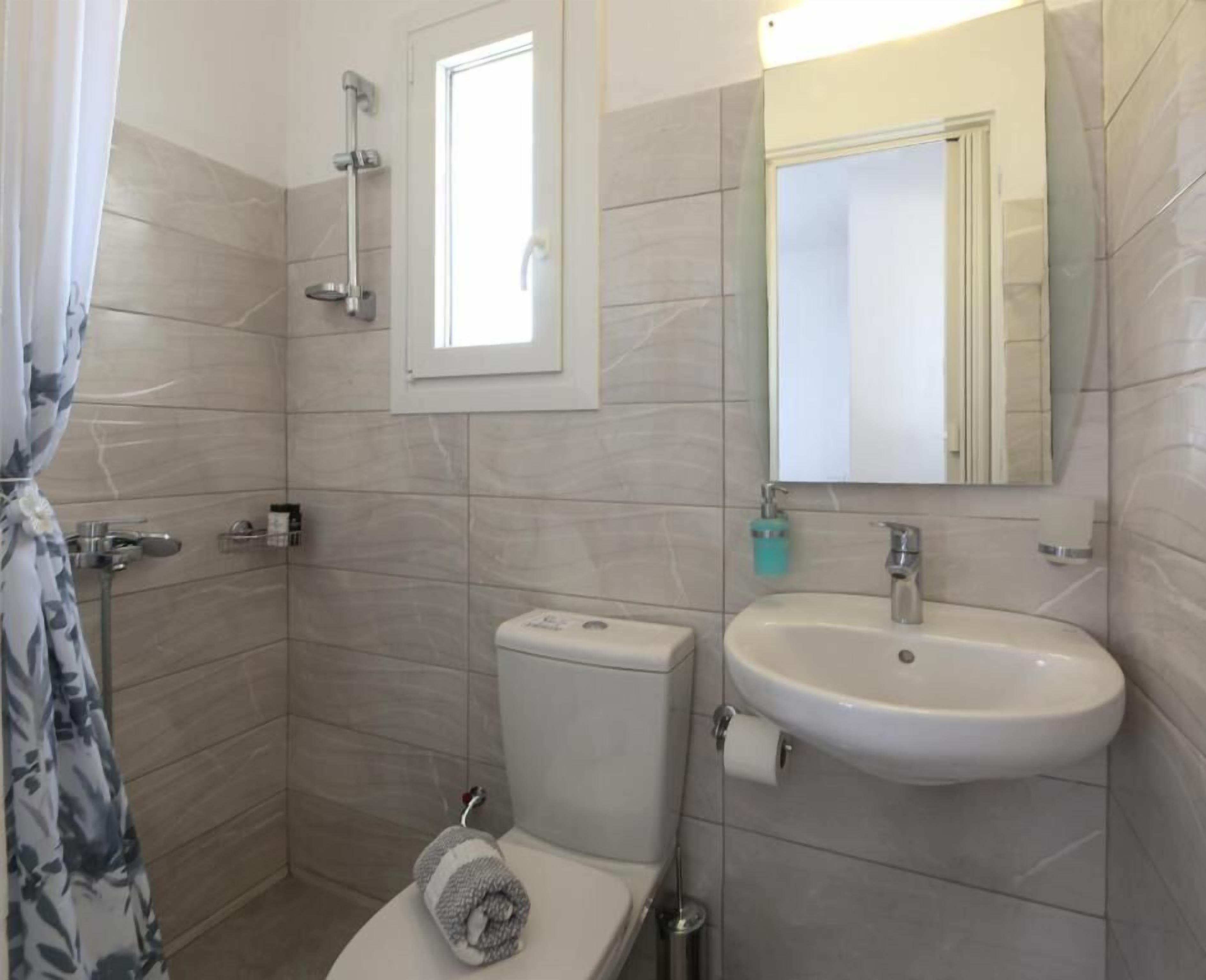 A bathroom with a toilet, bidet, sink, and a mirror.