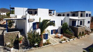 A white building with blue accents, a sign reading "Rhodis in Mykonos," and a small outdoor seating area with plants. - Holidays in Paros (Paros)