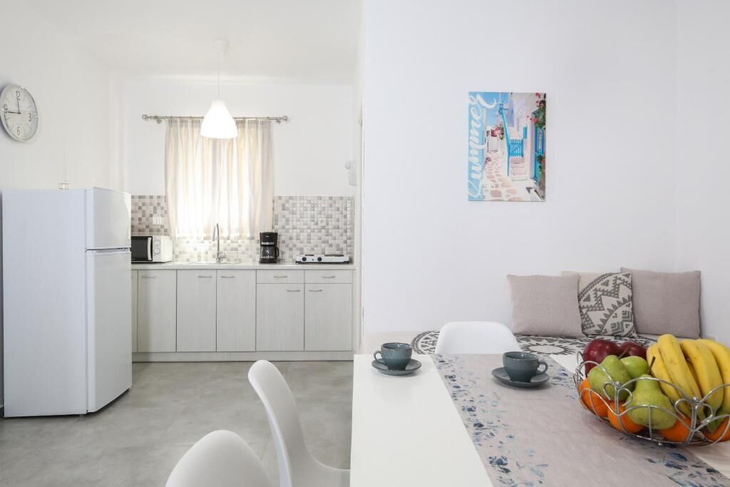Una cocina moderna con armarios blancos, un refrigerador y un comedor con una mesa para dos.