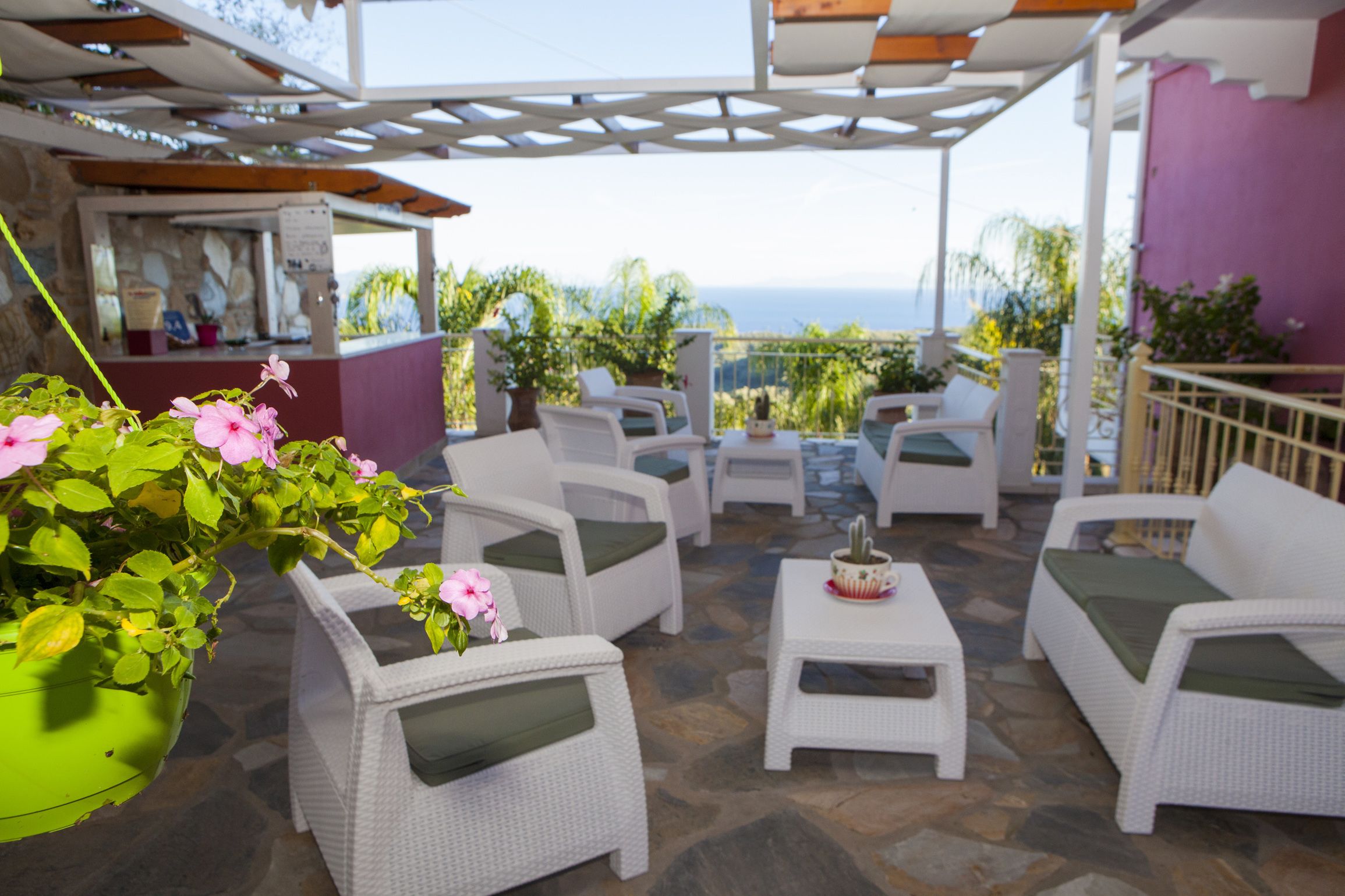 Un patio con mobiliario de mimbre blanco, una mesita y una planta colgante.