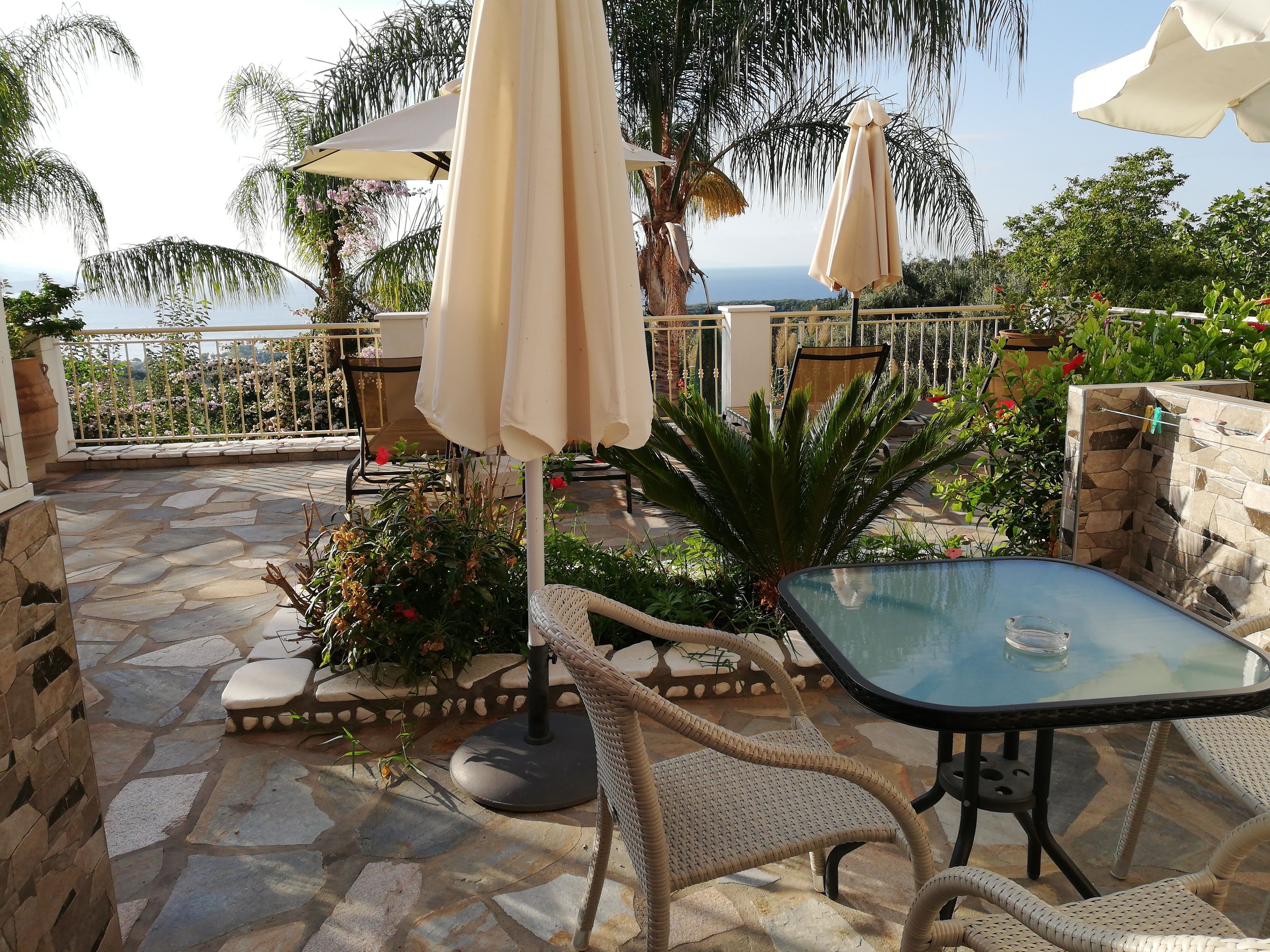 Un'area patio con pavimento in pietra, mobili in vimini e ombrelloni.