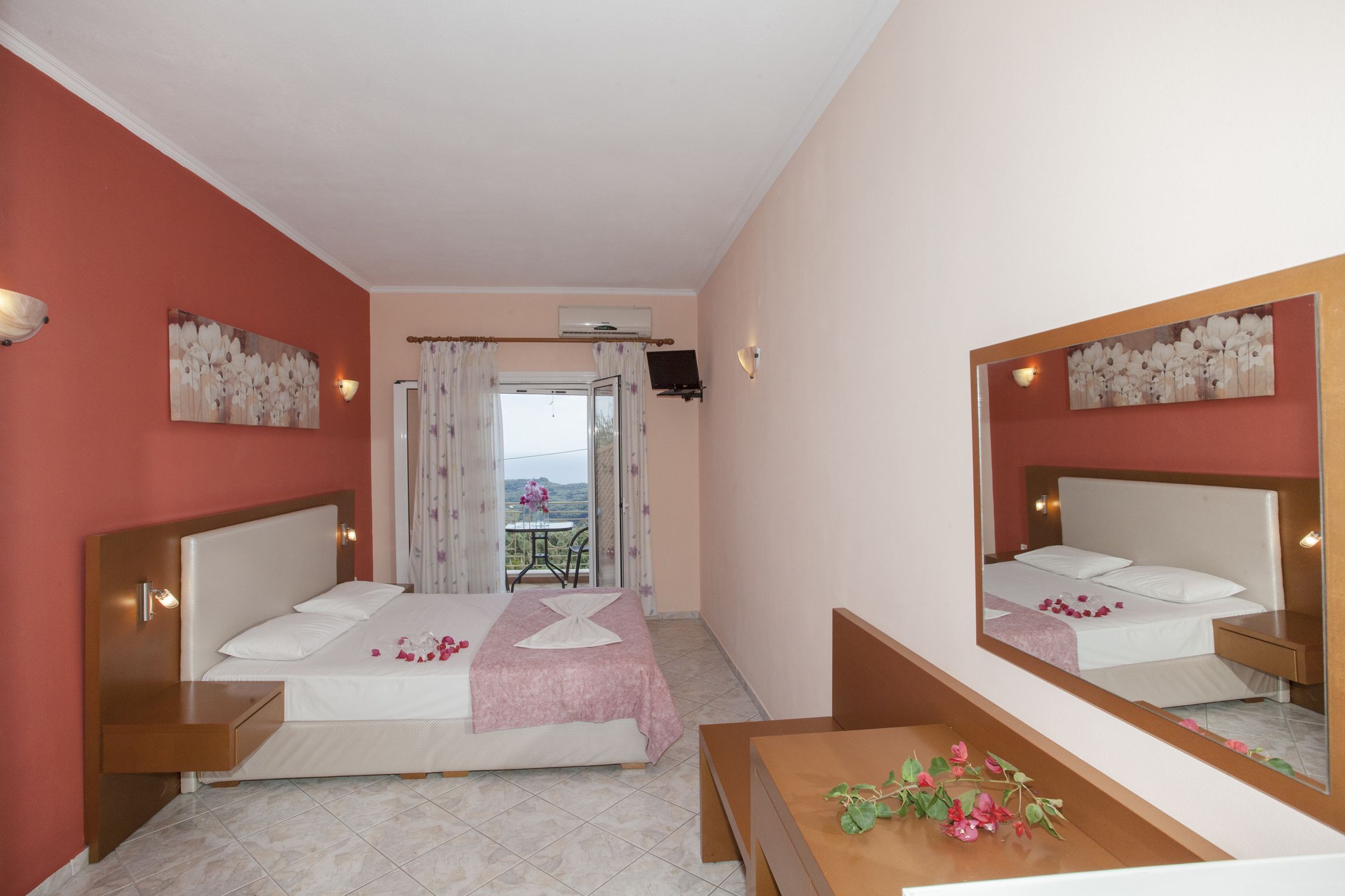 Una habitación de hotel con cama, escritorio, espejo y balcón con mesa y sillas.