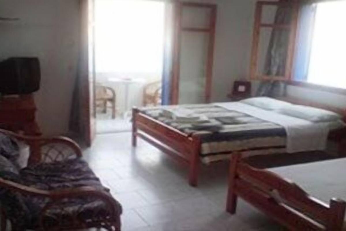 A room with a bed, a chair, a small table, and a window.