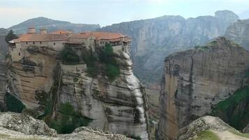 Un monastero arroccato su una scogliera rocciosa con vista panoramica sul paesaggio circostante.