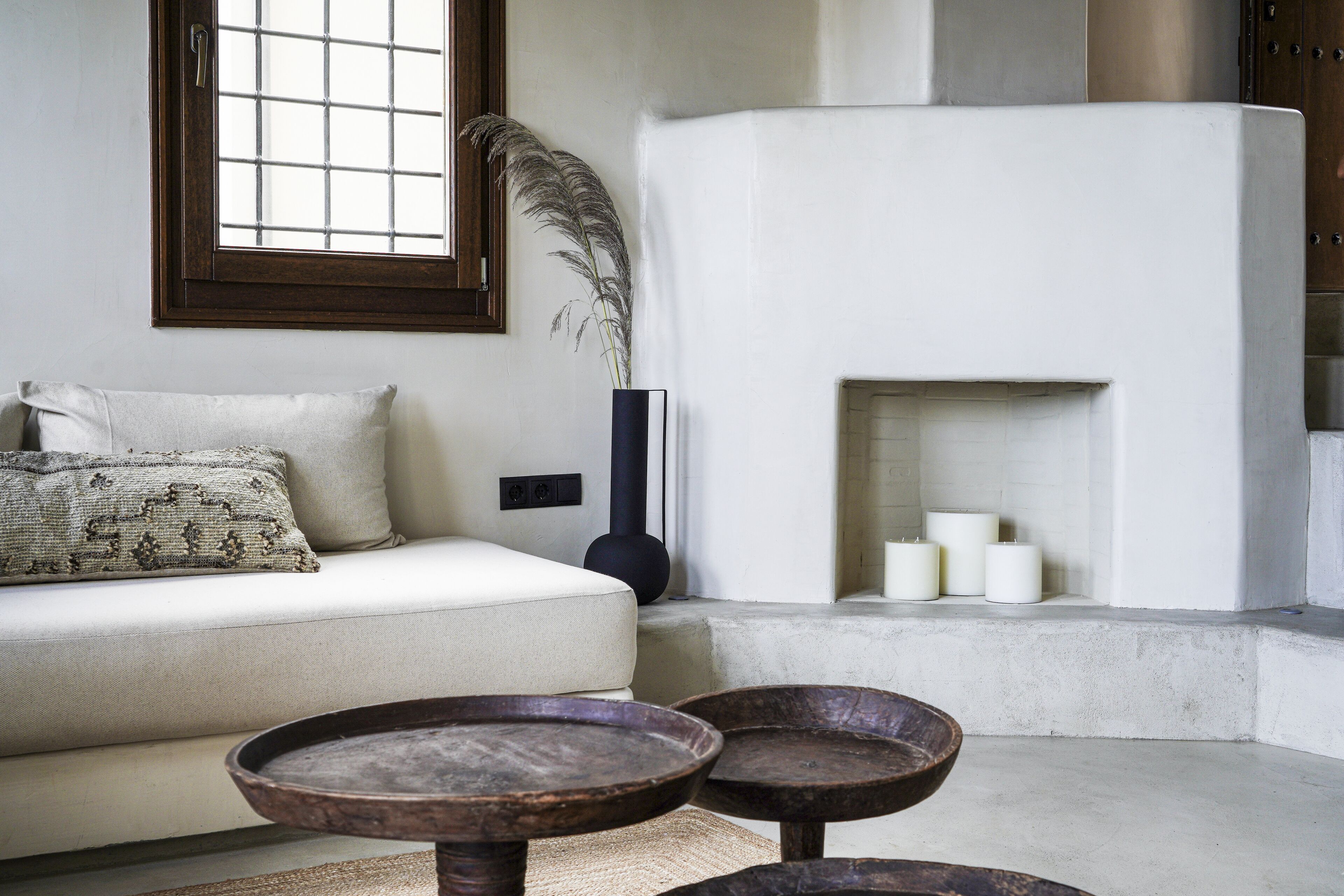 A modern living room with a sofa, a fireplace, and two wooden side tables.