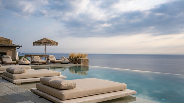 An infinity pool with lounge chairs and umbrellas, overlooking the sea. - Agapitos Villas & Guesthouses (Zagora-Mouresi)
