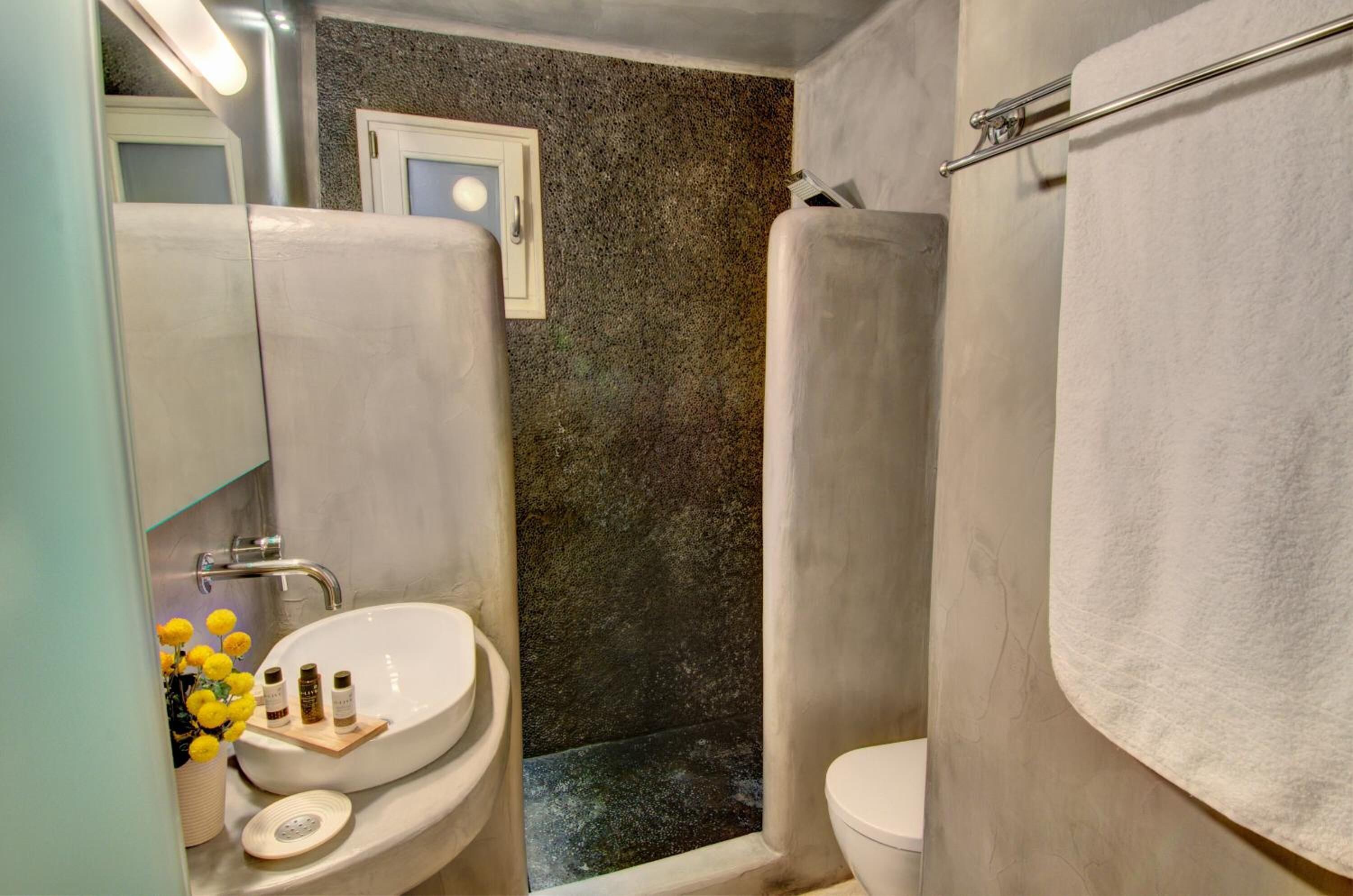 A bathroom with a white sink, a mirror, a towel rack, and a shower area.