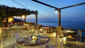 An outdoor dining area with tables and chairs, overlooking the sea. - Agapitos Villas & Guesthouses (Zagora-Mouresi)