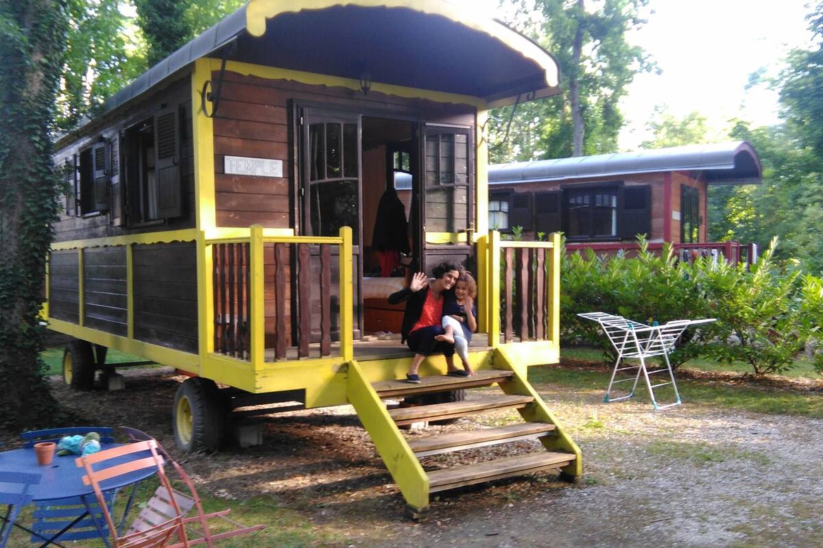 A yellow wooden structure with a porch, a sign reading "TEMPLE", and a small table with chairs.