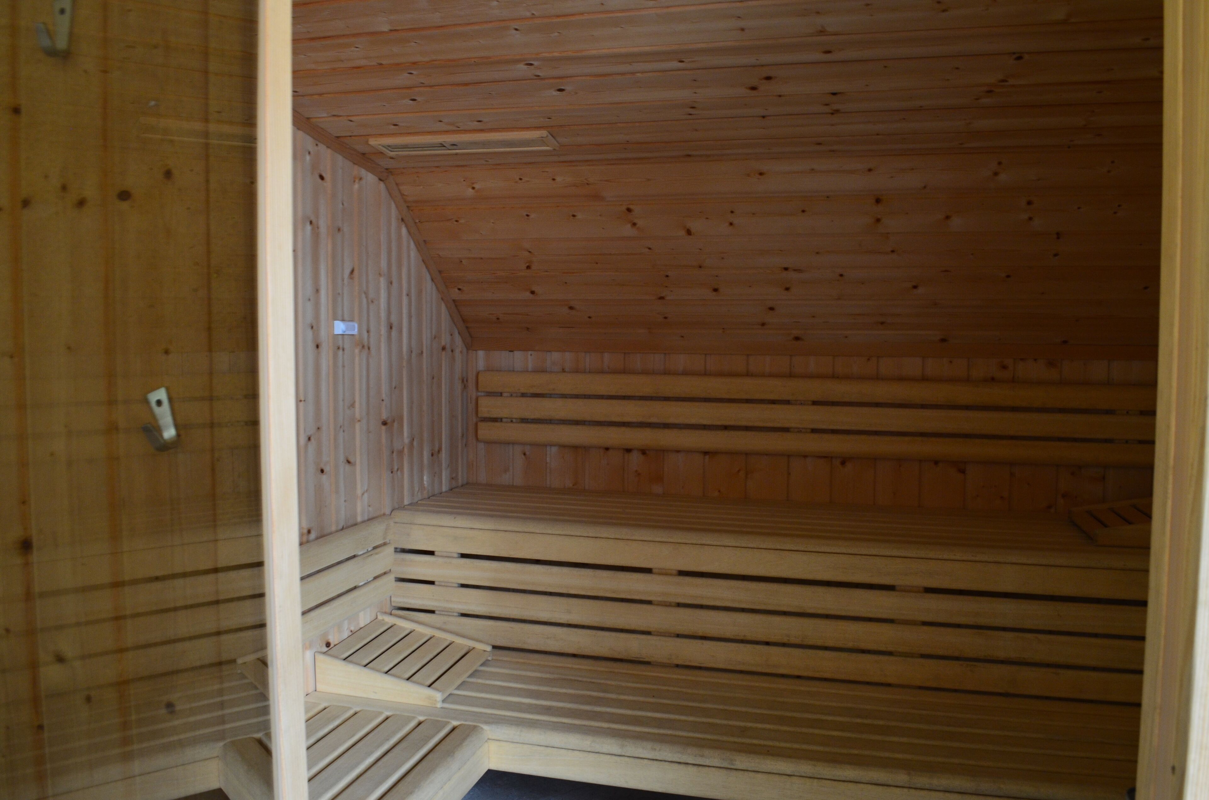 A sauna room with wooden walls and a sloped ceiling.