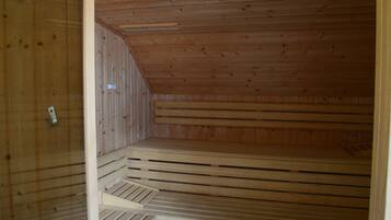 A sauna room with wooden walls and a sloped ceiling.