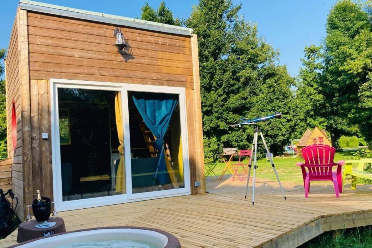 A wooden deck with a hot tub, a telescope, and a red chair.
