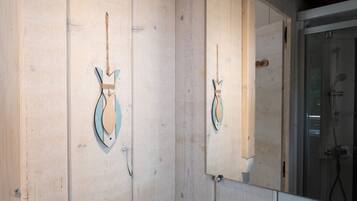 A wooden wall with a mirror reflecting a shower area.