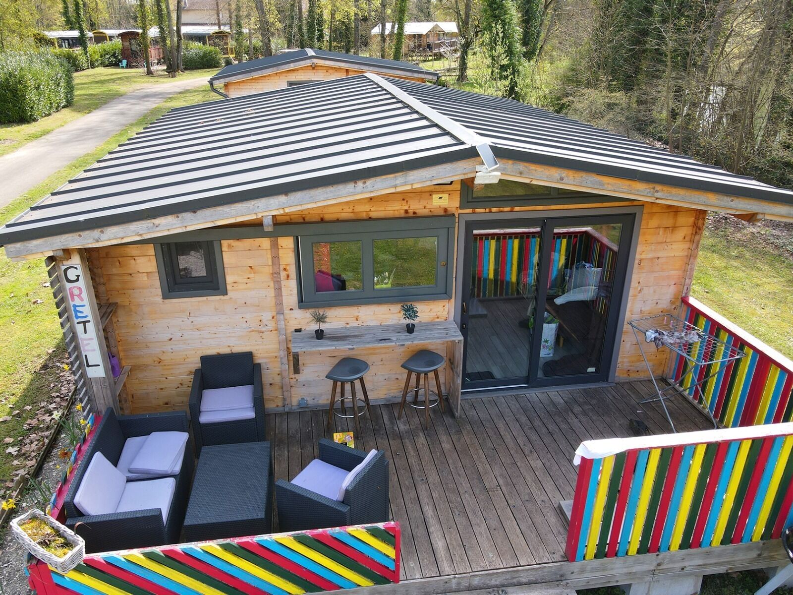 A wooden cabin with a deck, outdoor seating, a bar area, and a sliding glass door.