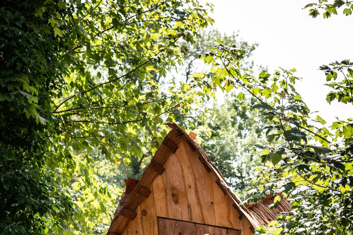 A wooden cabin with a small porch, a window, and a door. There are two chairs on the porch.