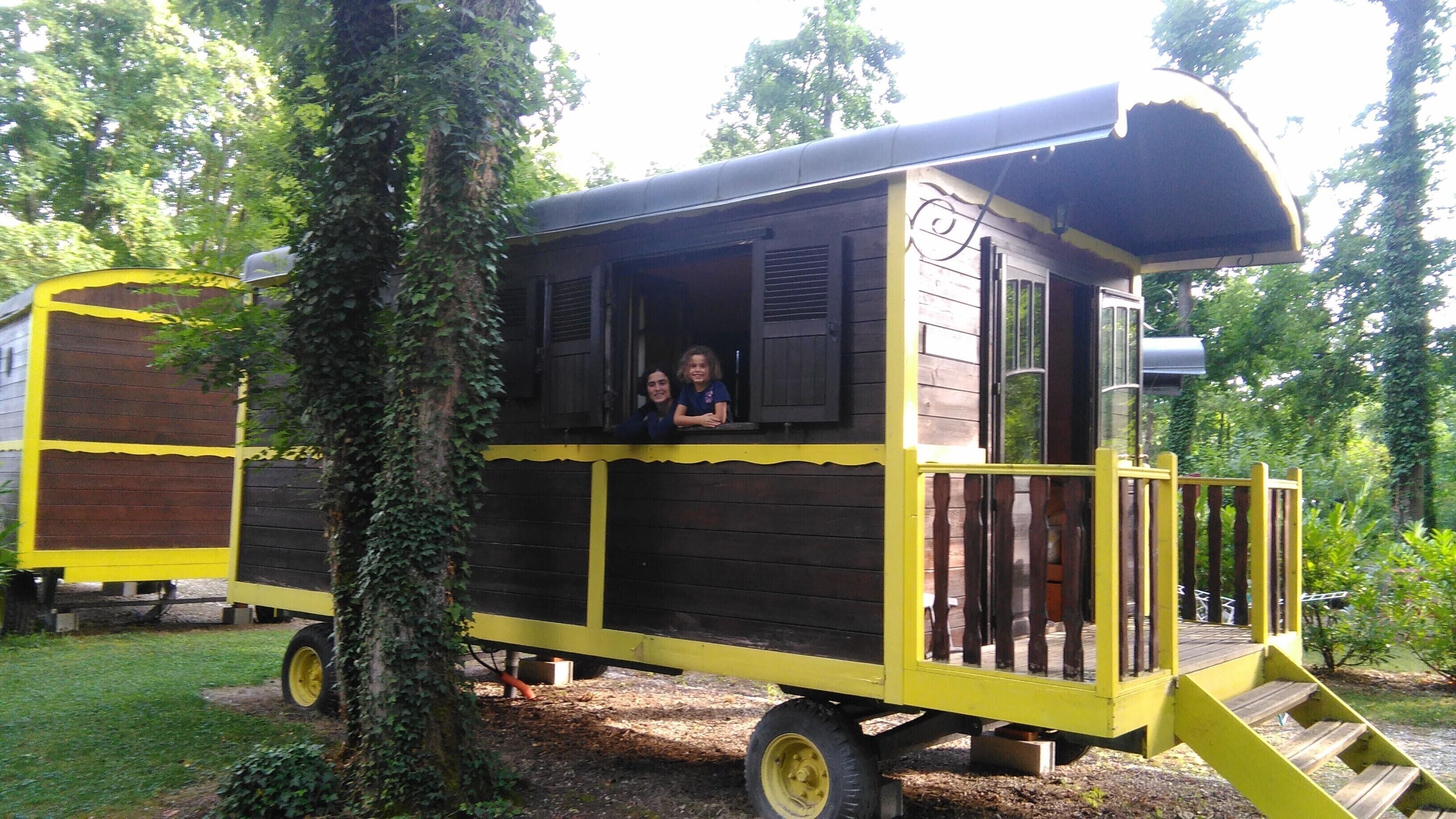 A yellow and black cabin with a small porch and a window.