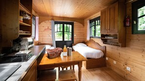A cozy cabin interior with a wooden interior, a bed, a dining table, and a kitchen area.
