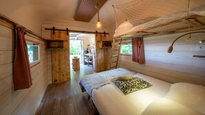 A wooden cabin with a bed, a desk, and a window.