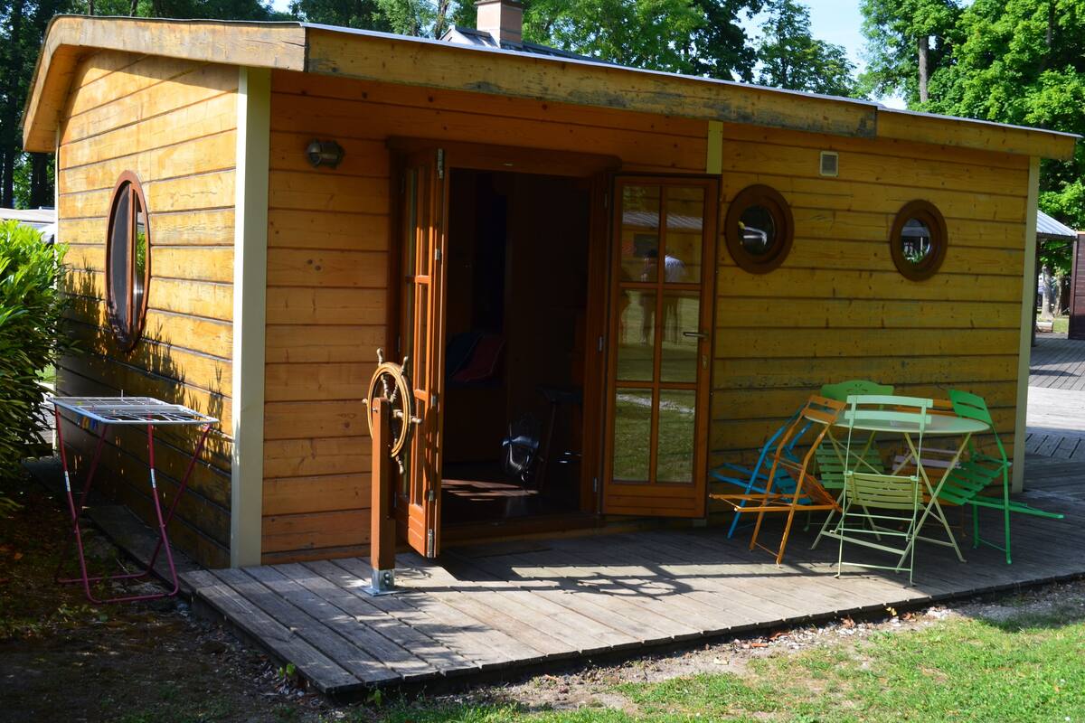 A wooden cabin with a door, a small table, and a chair outside.