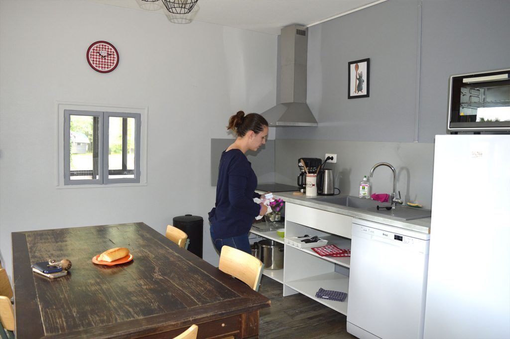Una cocina compacta con una mesa de comedor, lavavajillas y ventana.